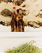 Zwei Kräuterlikörflaschen stehen auf einer Ablage vor Steinwand, Hierbas