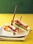 Club sandwich with turkey cutlets on white bread halves on plate