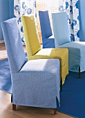 Mehrere Stühle in diversen Blautönen stehen im Halbkreis in Esszimmer