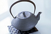 Japanese teapot on coaster on white background