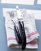 Close-up of carving knife and fork placed on napkin