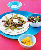 Fajitas with beef and bowl of salsa on serving plate
