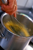 Close-up of sugar and eggs being beaten until fluffy with whisk in pot