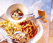 Various pasta dishes on plate and in bowl, elevated view