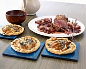 Goose breast with coriander, apples and three small pizzas on table