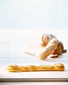 Eine Stange Baguettebrot, andere Brote im Hintergrund