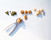 Different types of nuts and nutcracker on white background, overhead view