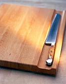 Close-up of bread knife on chopping board made of buchholz wood