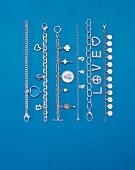 Different types of silver bracelets on blue background