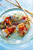 Close-up of fish soup with monkfish heads and herb vinaigrette on glass plate