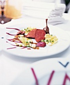 Bresse pigeon with lettuce, peas and garlic shoots on plate