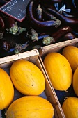 Honeydew melons and eggplants in crates, close-up