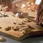 Close-up of walnuts being chopped by knife on chopping board