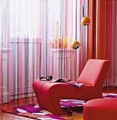 Living room with red armchair in front of string curtain