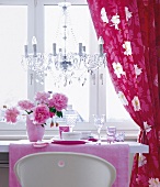 Dining room with set table, chandeliers and curtains beside window