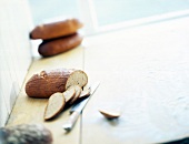 Loaf of bread and slices with knife on kitchen table