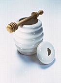 White honey pot with wooden spiral on white background