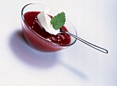 Red fruit jelly with yogurt and lemon balm leaf in bowl on white background