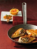 Stuffed chicken breasts in frying pan against red background