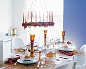 Festively decorated table in gold with lit candles, cutlery and chandelier