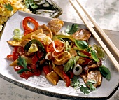 Asian stir fry vegetables with fillet strips kept with chopsticks on white serving dish