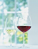 Weinglas mit Rotwein, im Hintergrund mit Weißwein.