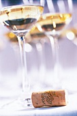 Close-up of white wine glasses with a wine cork