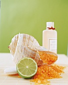 Sea salt, bath shell, lime and oil bottle on mat