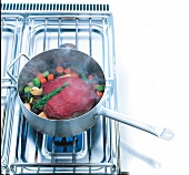 Roast beef cooked with vegetables and rosemary in saucepan