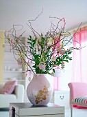 Zweige mit Osterschmuck in rosafarbener Vase
