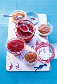 Three bowls of rhubarb and orange jam, two bowls with rhubarb and raspberry jam
