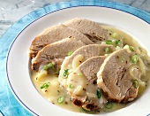 Sliced meat with onions on plate