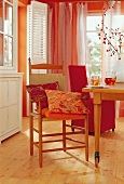 Dining room in orange and red tones with shaker chair and floral pattern cushion