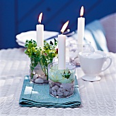 Kerzen als Dekoration auf einem Gartentisch, geschmückt mit Blumen