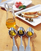 Olive oil in spoon and in a carafe