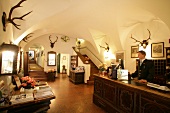 Man at reception counter of hotel decorated with antlers, Austria