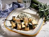 Skewered fish with zucchini besides risotto and sage on plate