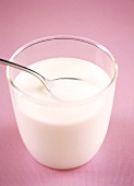 Yogurt in jar with spoon on pink background