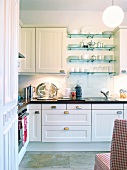 White fitted kitchen with glass shelf and lamp