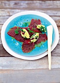 Marinated tuna with crushed potatoes, olives and rocket leaves on plate