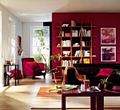 Sofa next to side table, red armchair and bookshelf on red wall in living room