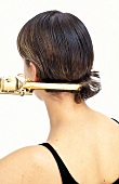 Rear view of woman turning her hair tips inward with curling tong