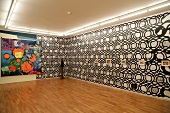 Person standing in exhibition gallery with patterned wall, Germany