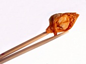 Chopsticks with dim sum jiaozi made of minced pork, chives and soy sauce