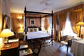 View of hotel's bedroom with poster bed, curtains and illuminated lamps, Belgium