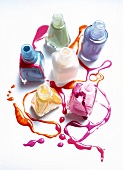 Six bottles with pastel nail polish smeared on white background