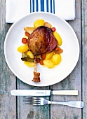 Roasted duck leg with curry, carrot and potatoes served on plate