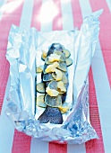 Salmon trout with lemon slices and butter on silver foil