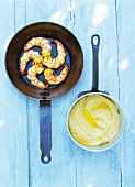 Prawns with mashed potatoes in sauce pan on blue wooden surface