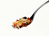 Risotto with black olives and squid on fork against white background